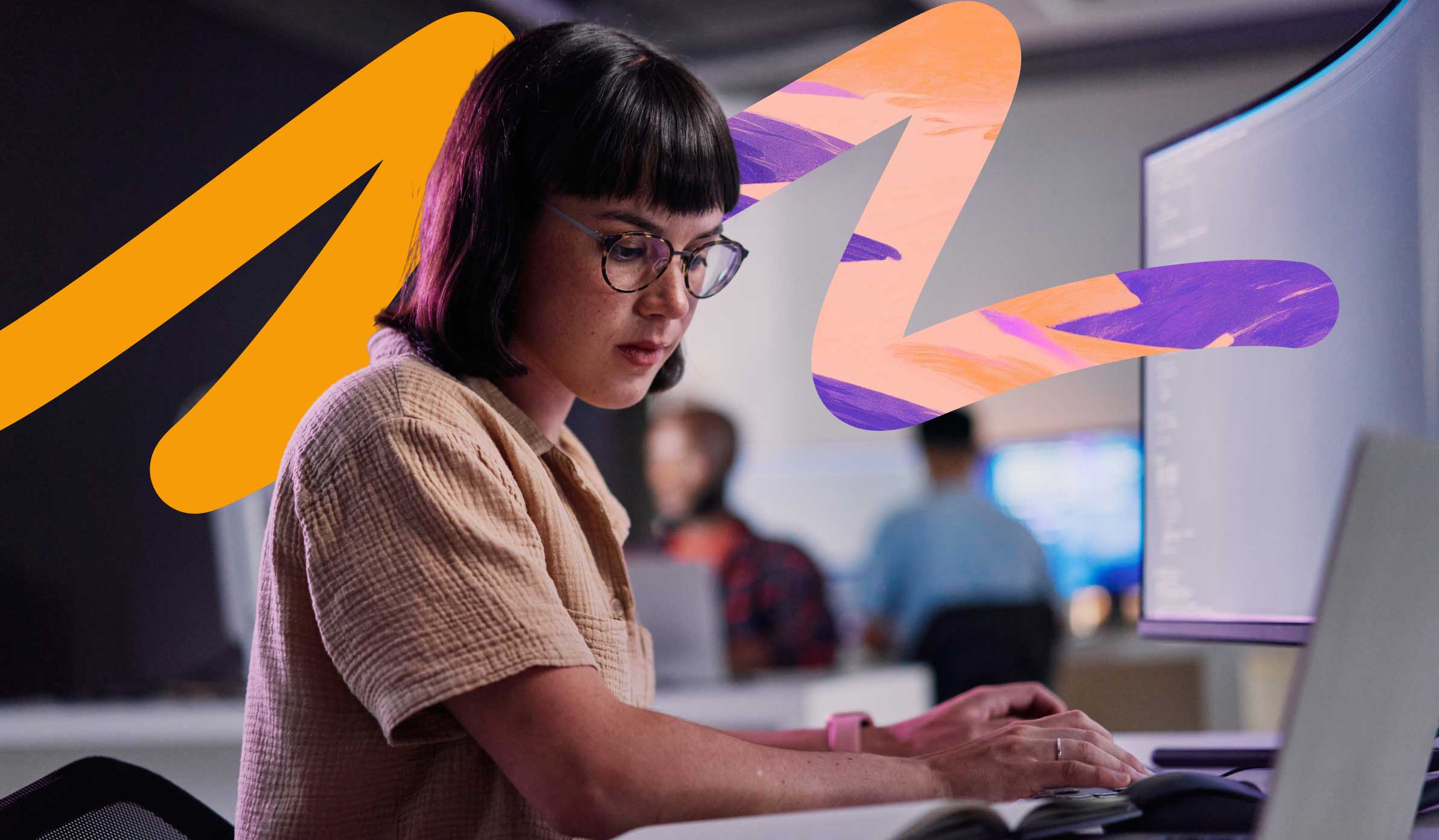 Young female employee focused at her desk typing and referencing her notebook